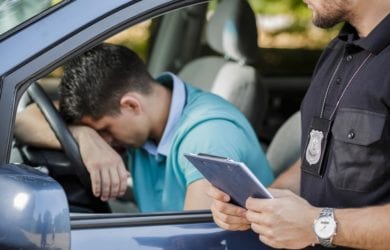 young driver with head down with police officer giving ticket